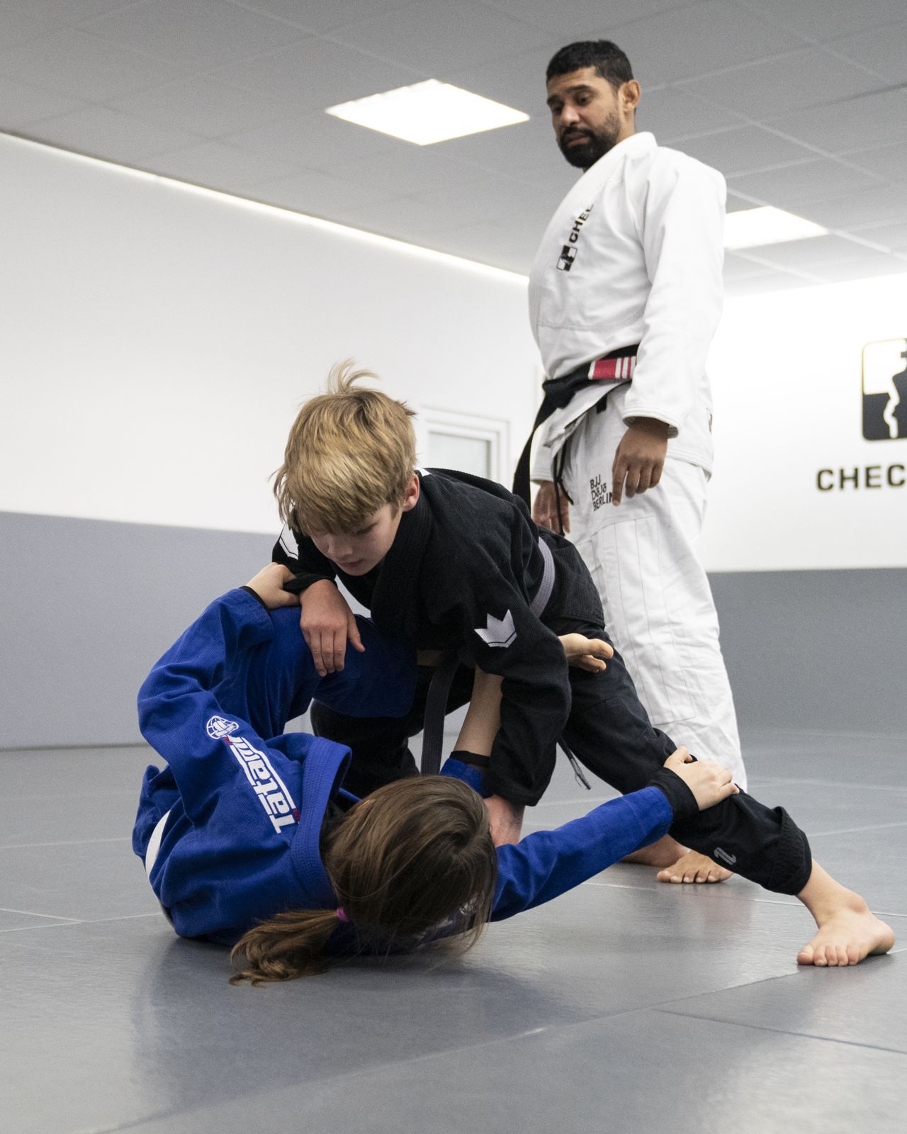 Trainer begleitet zwei Kinder beim Rollen im BJJ DOJO Berlin. Foto: Photo Blackbelt.
